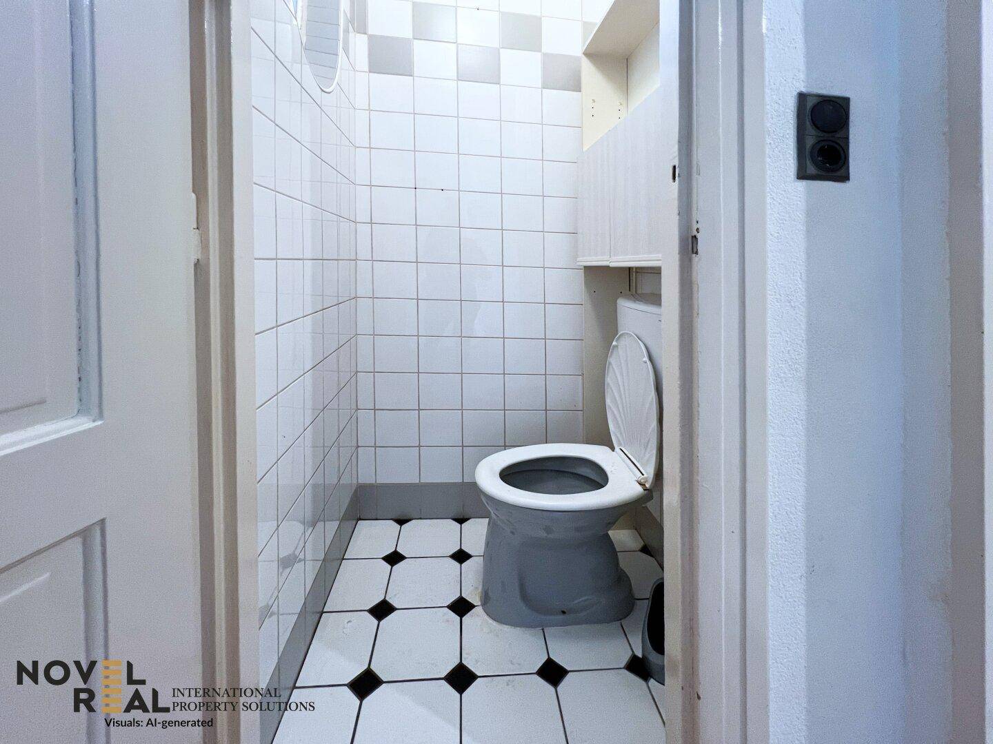 Separate Toilette mit weißen Fliesen und einem dunklen Fliesenbodenmuster.