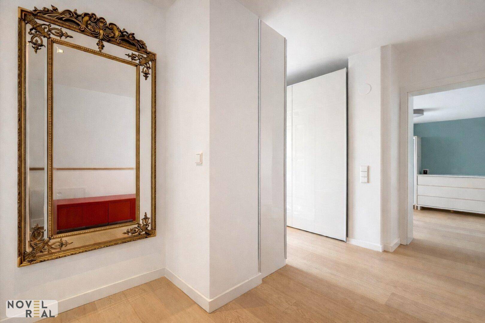 Eingangsbereich mit elegantem, verziertem Spiegel und hellem Holzboden.