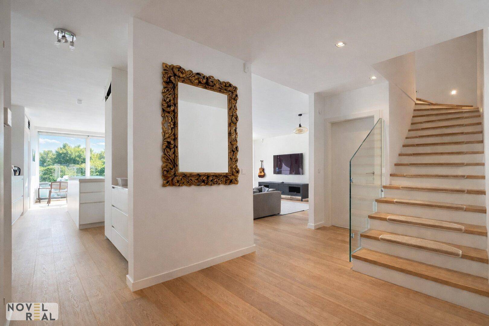 Geräumiger Flur mit eleganter Treppe, großem Spiegel und Zugang zum Wohnbereich.