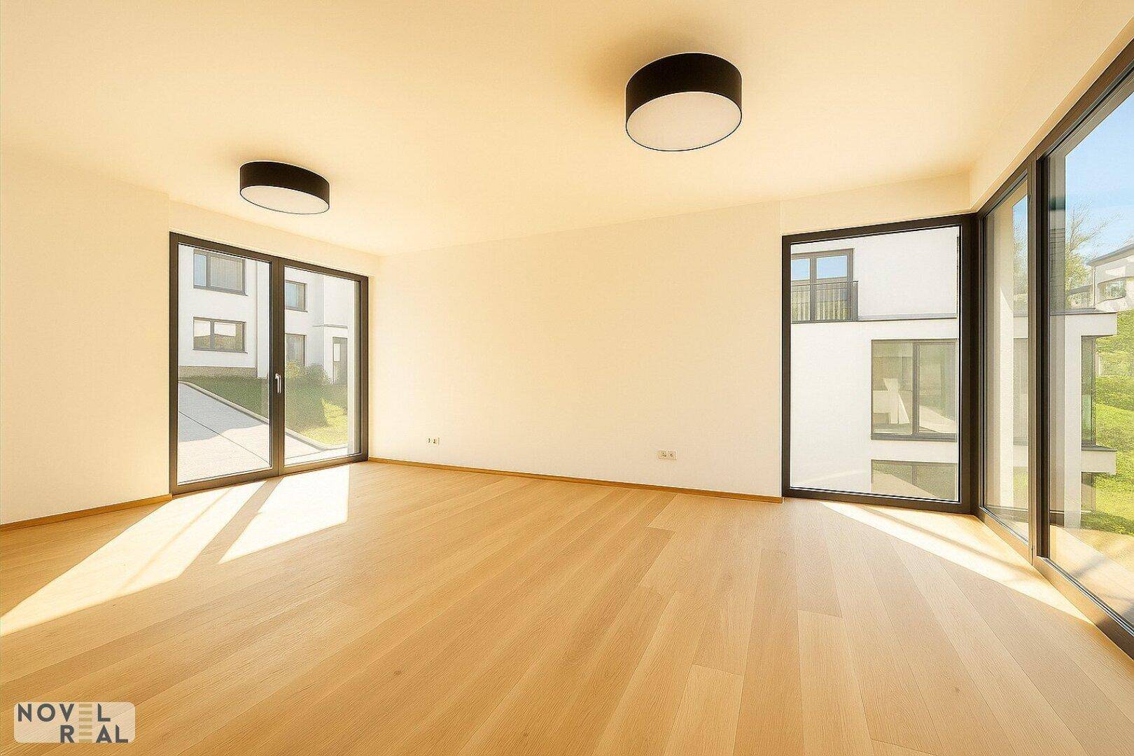 Heller Wohnraum mit großen Fenstern, die viel Tageslicht hereinlassen und einen Blick nach draußen bieten.