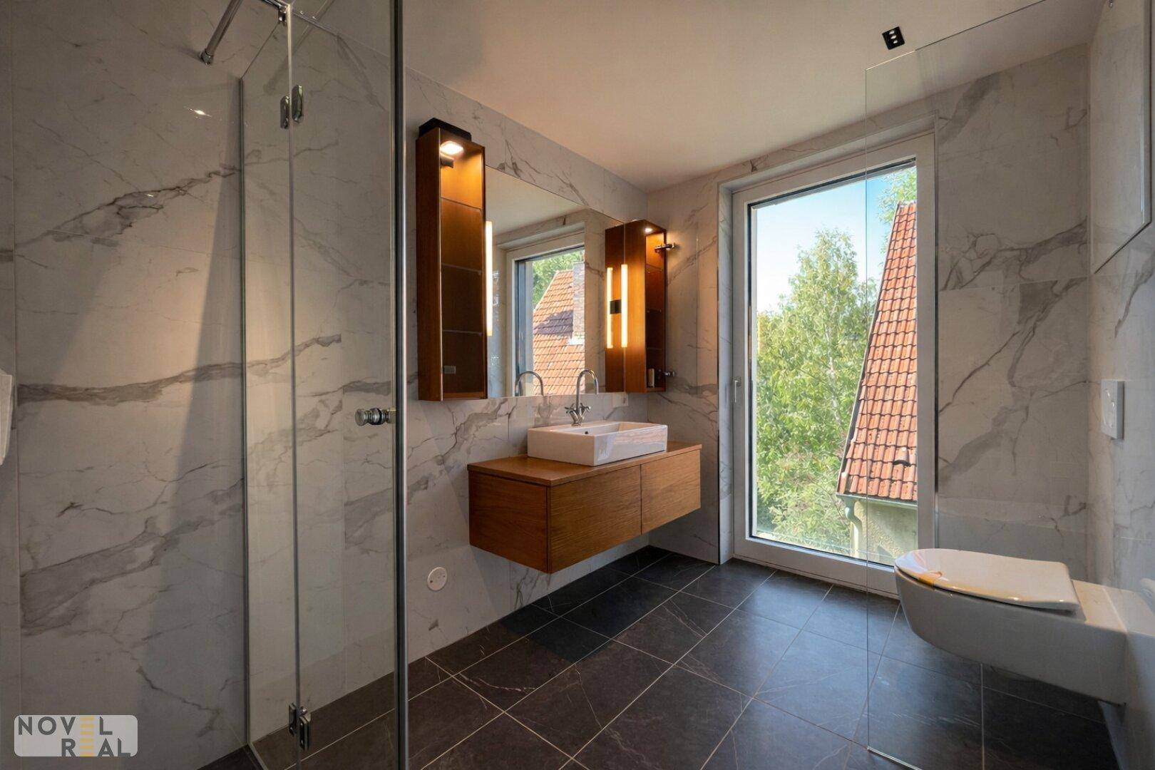 Modernes Badezimmer mit Duschkabine, schwebendem Waschtisch und Fenster mit Blick ins Grüne.