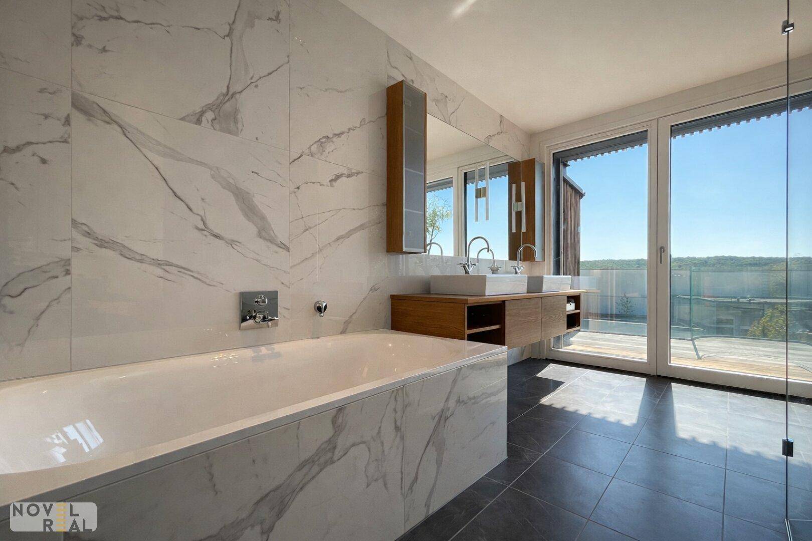 Luxuriöses Badezimmer mit Badewanne, Doppelwaschbecken und großen Fenstern zur Terrasse.