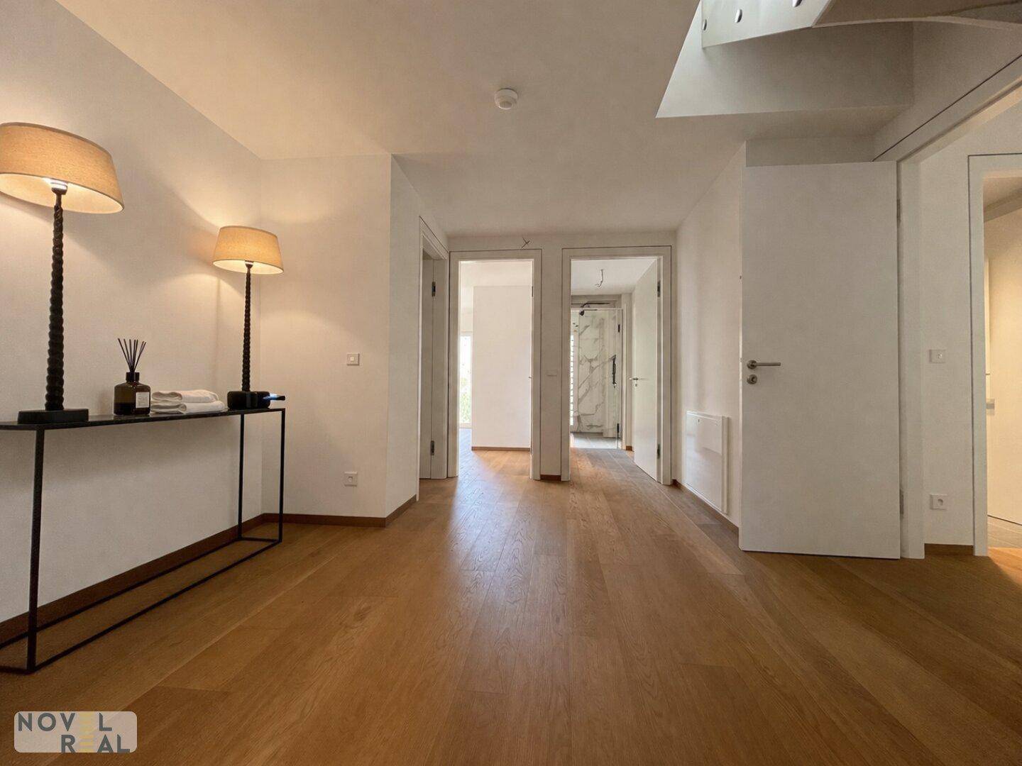 Heller Flur mit Holzboden, indirekter Beleuchtung und Zugang zu mehreren Räumen.