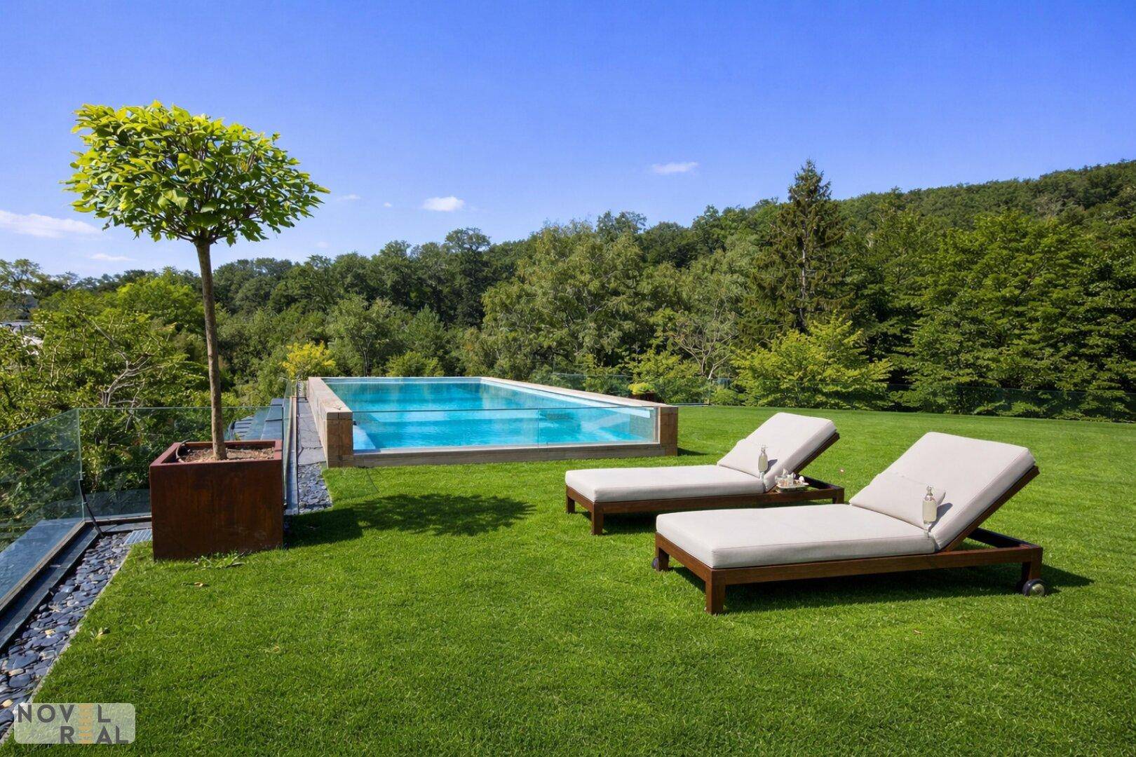 Moderner Infinity-Pool im weitläufigen Garten mit bequemen Liegestühlen und Panoramablick ins Grüne.