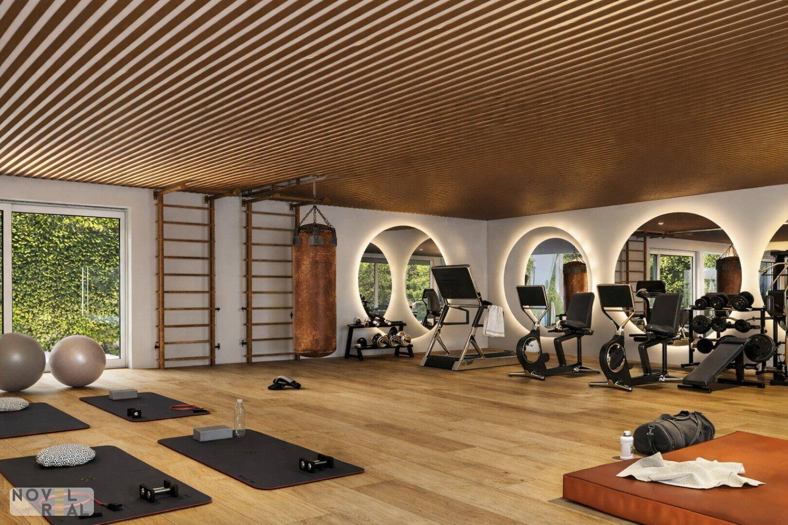 Moderner Fitnessraum mit Holzboden, Sprossenwänden und verschiedenen Trainingsgeräten für Sportbegeisterte.