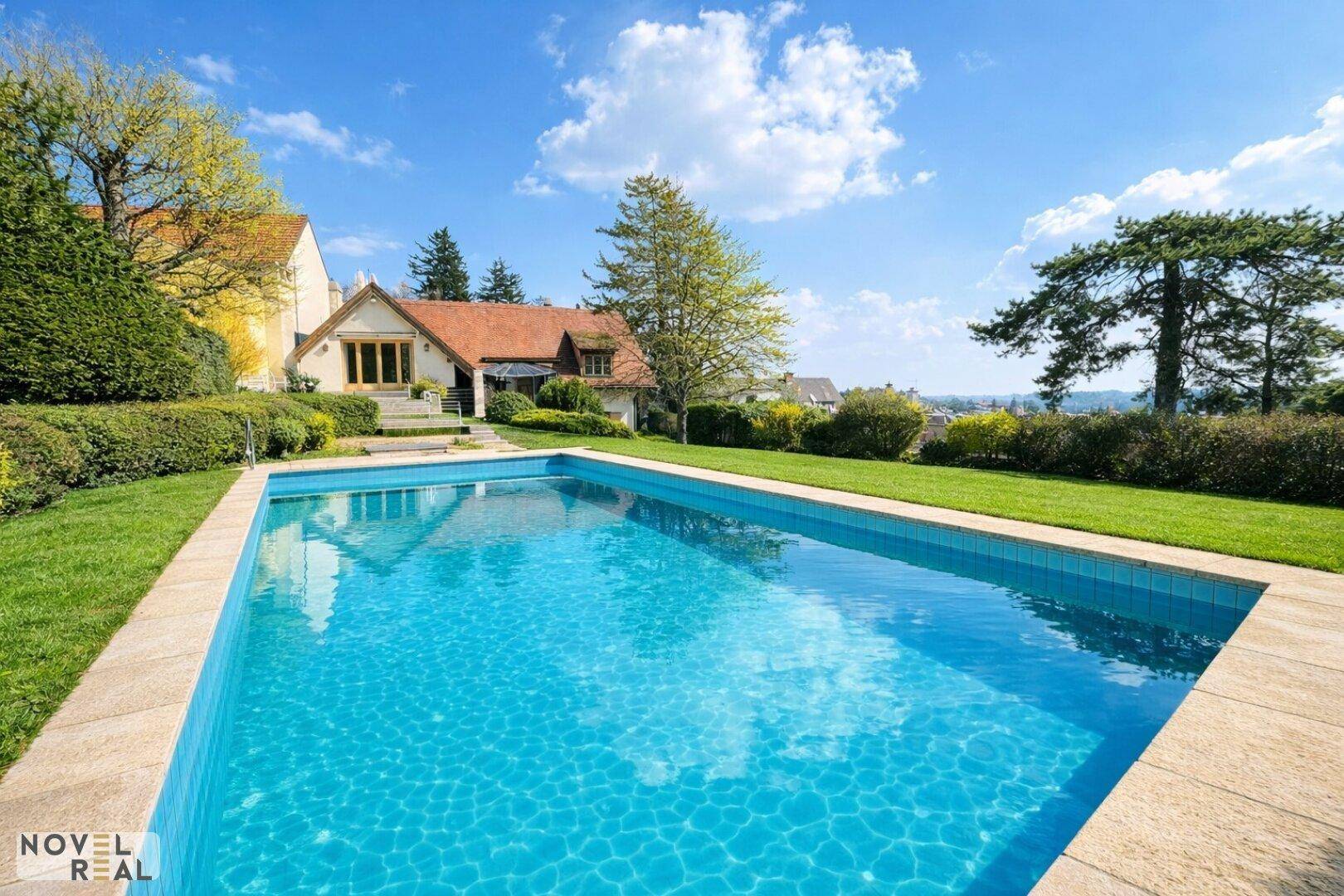 Weitläufiger Garten mit großem Swimmingpool und Blick auf die umliegende Landschaft.