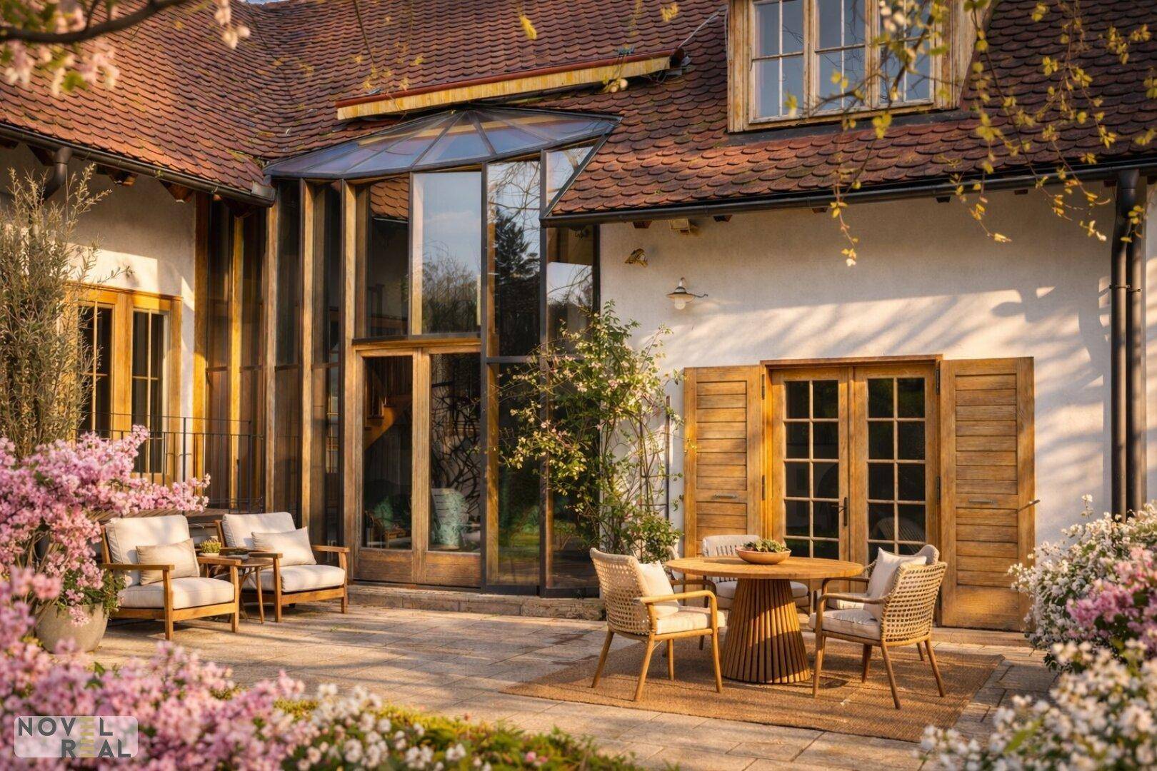 Charmante Terrasse mit Sitzgelegenheiten, umgeben von blühenden Pflanzen und dem Haus.