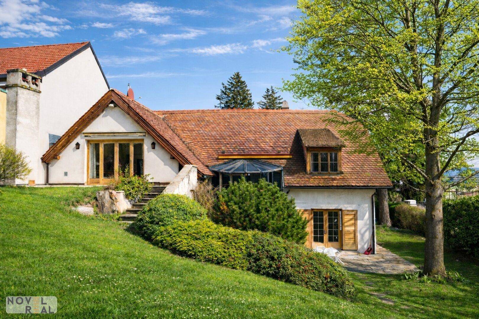 Traditionelles Landhaus mit Ziegeldach, großen Fenstern und gepflegtem Gartenbereich.