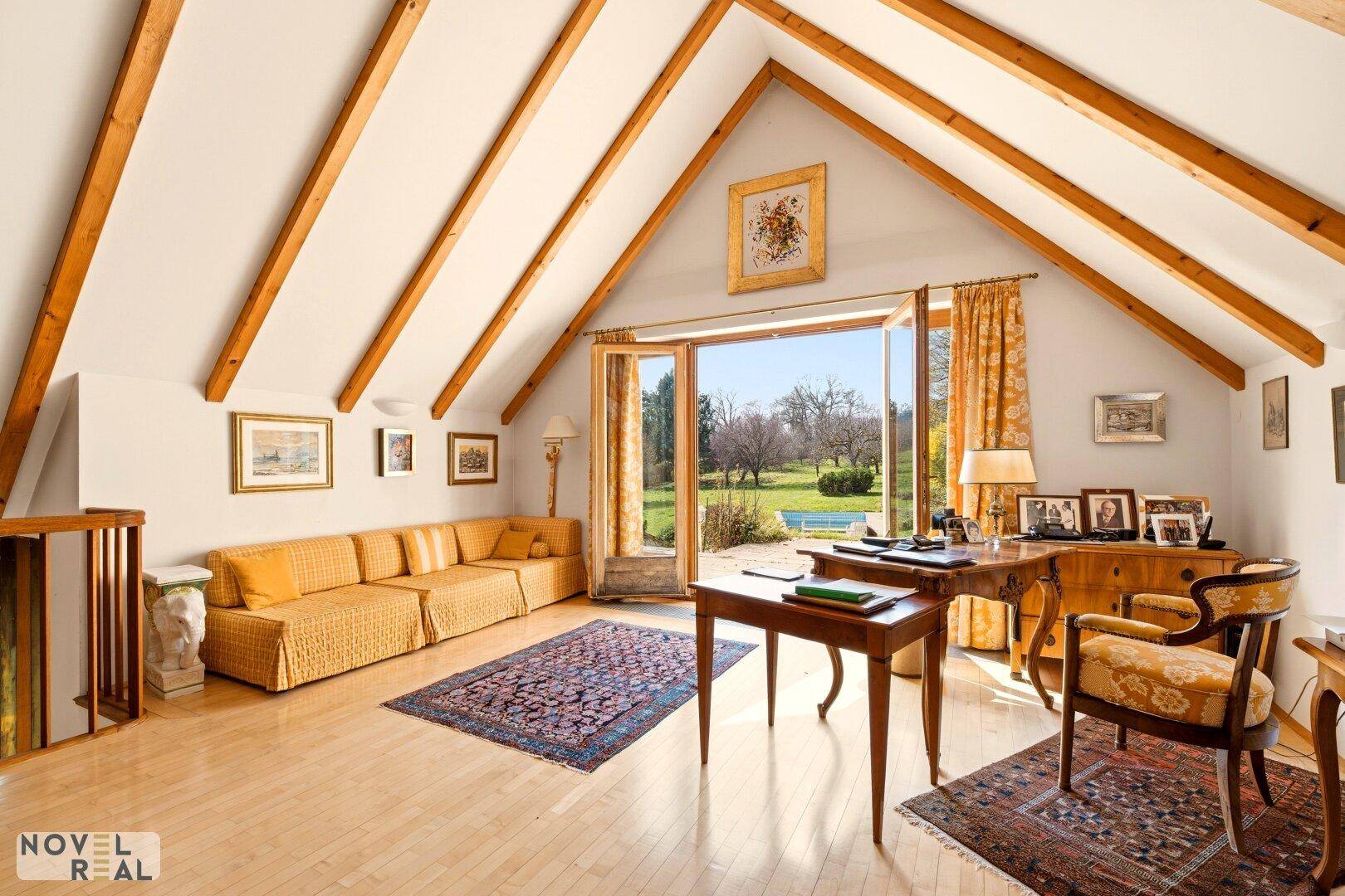 Helles Arbeitszimmer mit Holzbalken, Parkettboden und Zugang zum Garten.