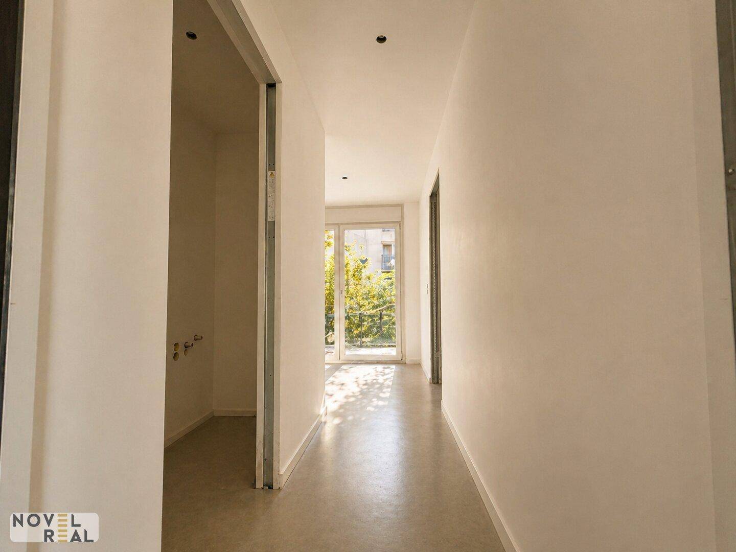 Heller Flur mit Betonboden und Zugang zu weiteren Räumen, lichtdurchflutet.
