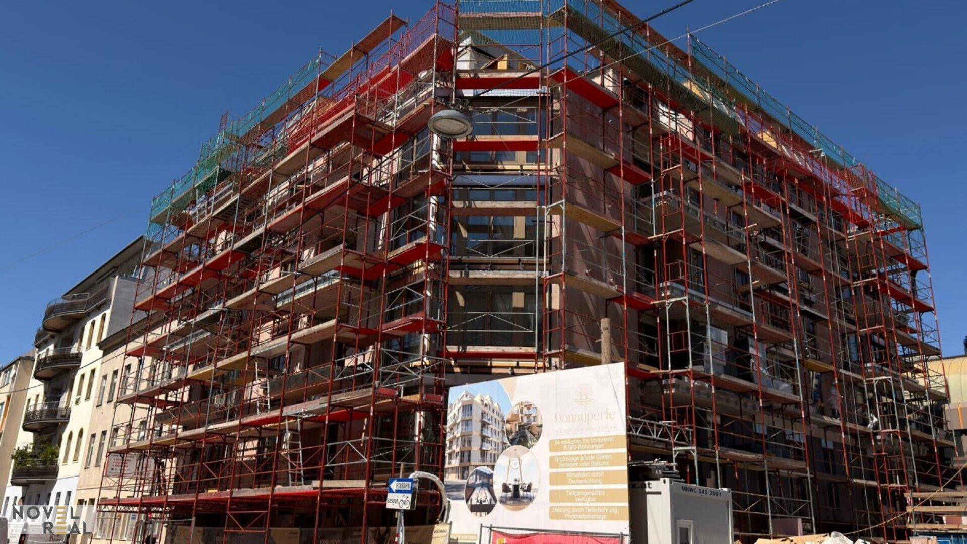 Gebäude im Bau mit Gerüst, das die zukünftige Fassade verdeckt und auf eine moderne Architektur hindeutet.