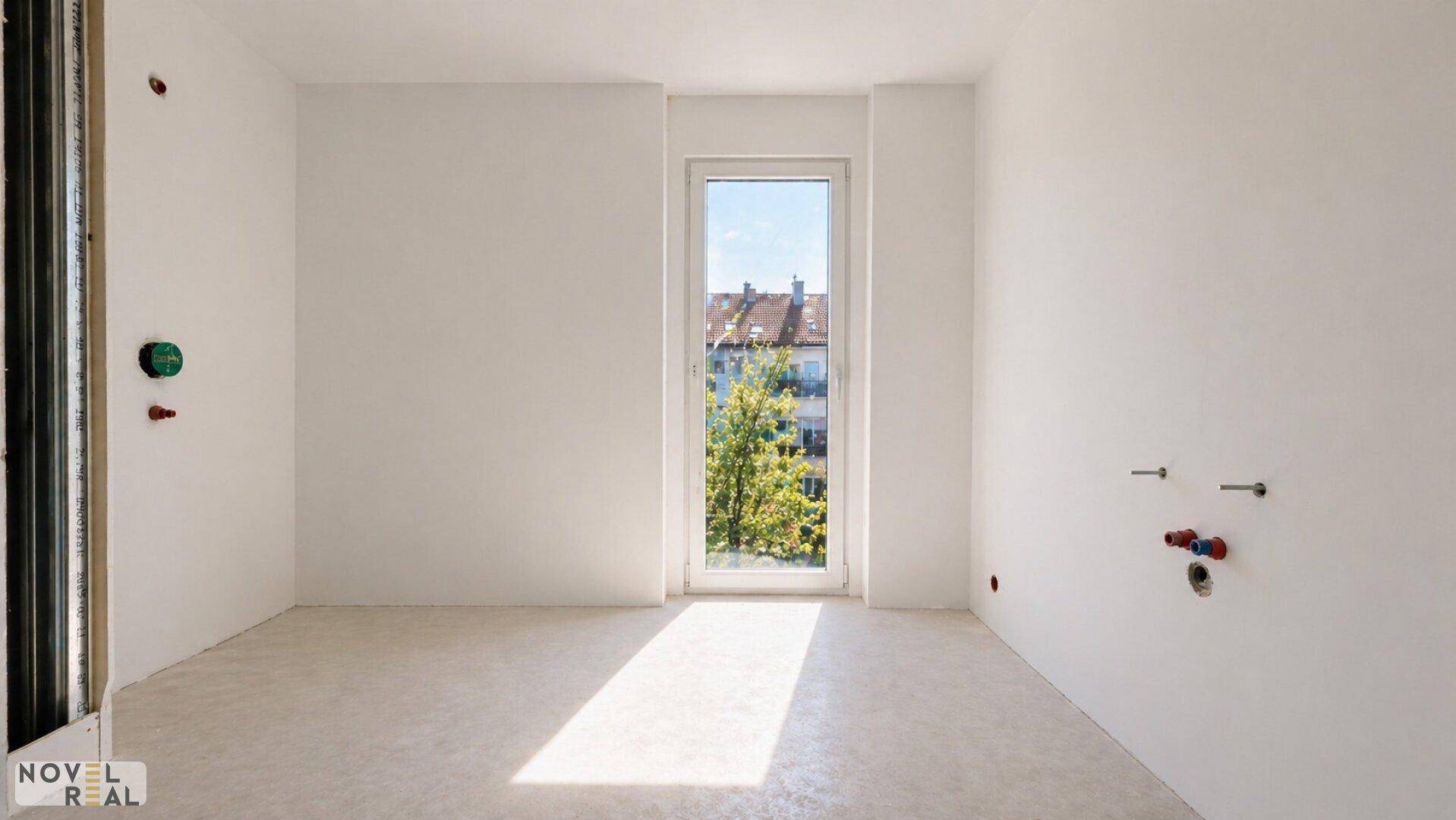 Unfertiges Badezimmer im Rohbau mit Anschlüssen für Sanitäranlagen und Fenster.