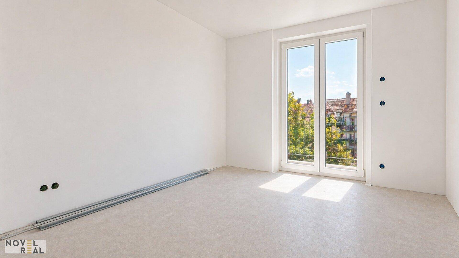 Unmöbliertes Zimmer im Rohbau mit großem Fenster, das viel Tageslicht hereinlässt.