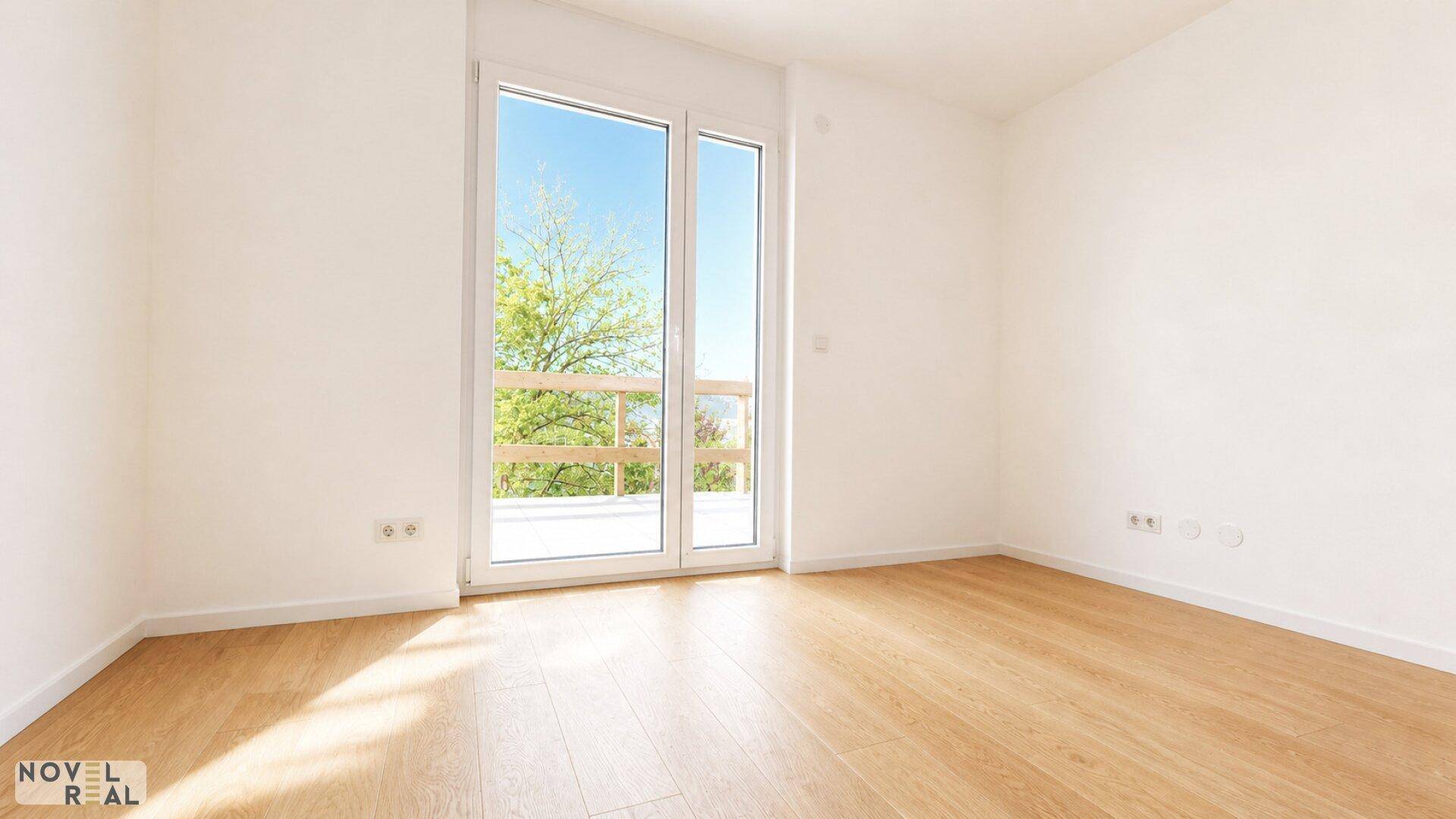 Lichtdurchflutetes Zimmer mit Holzboden und bodentiefen Fenstern, ideal als Schlaf- oder Arbeitszimmer.