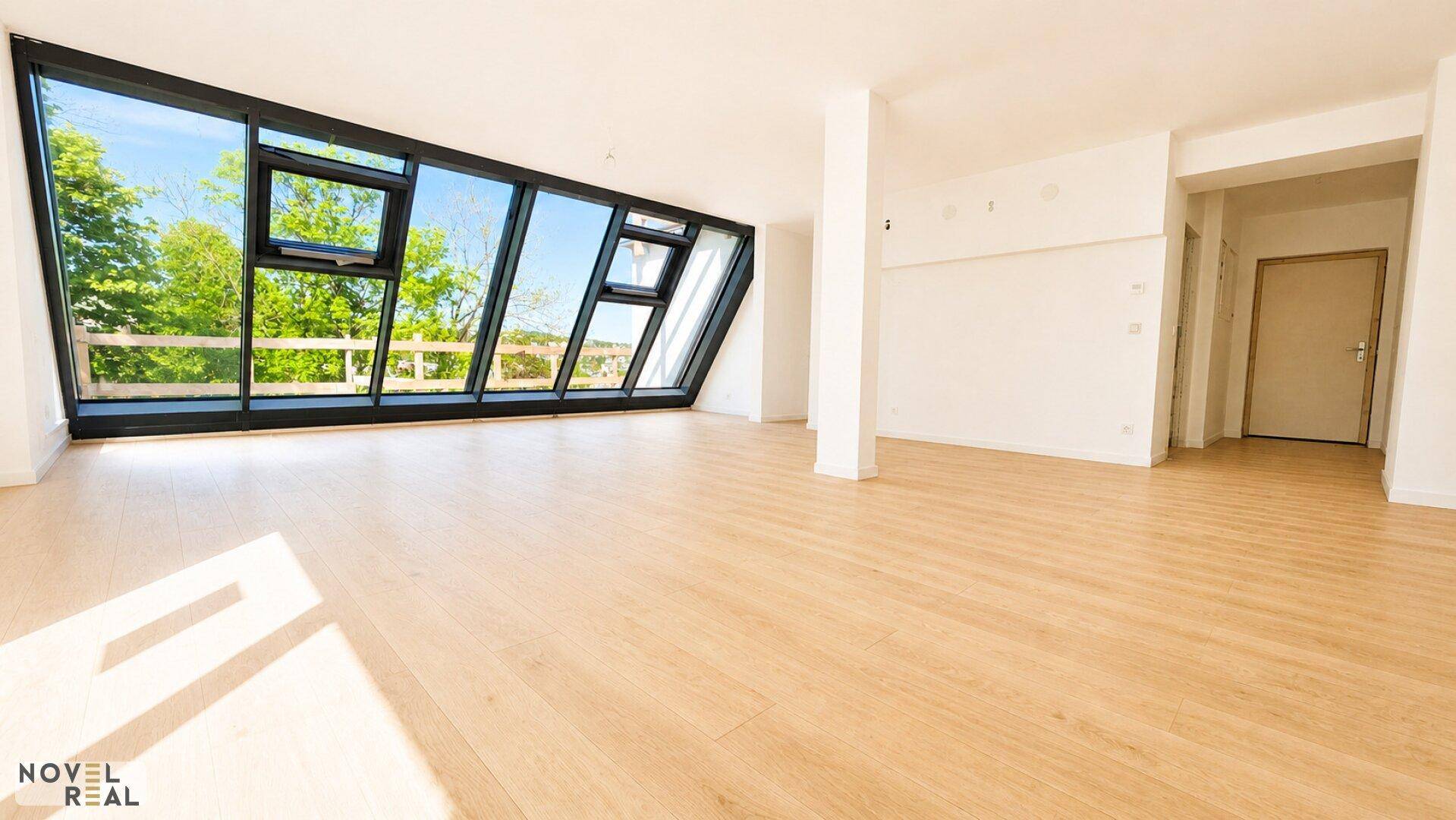Geräumiger, heller Wohnbereich mit großen Fenstern und Holzboden, ideal für individuelle Gestaltung.
