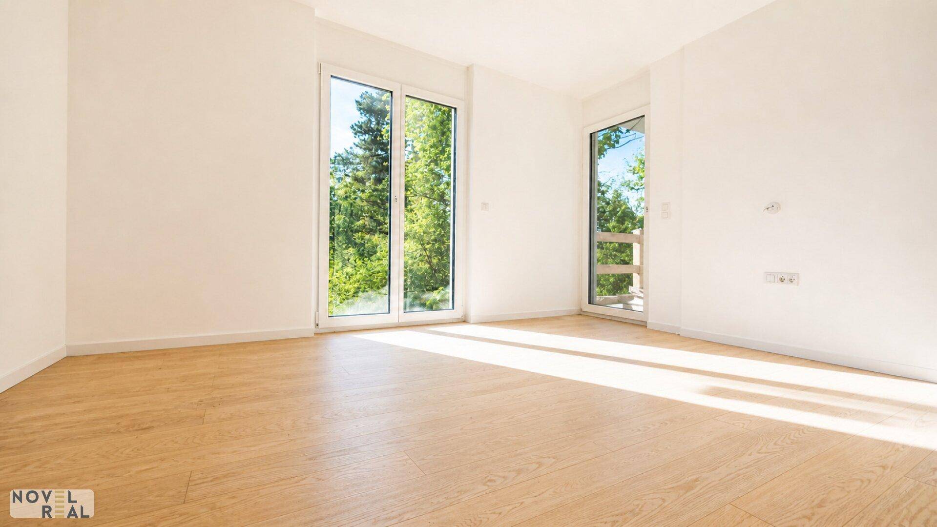 Helles Zimmer mit Holzboden und großen Fenstern, die viel Tageslicht und Grünblick bieten.