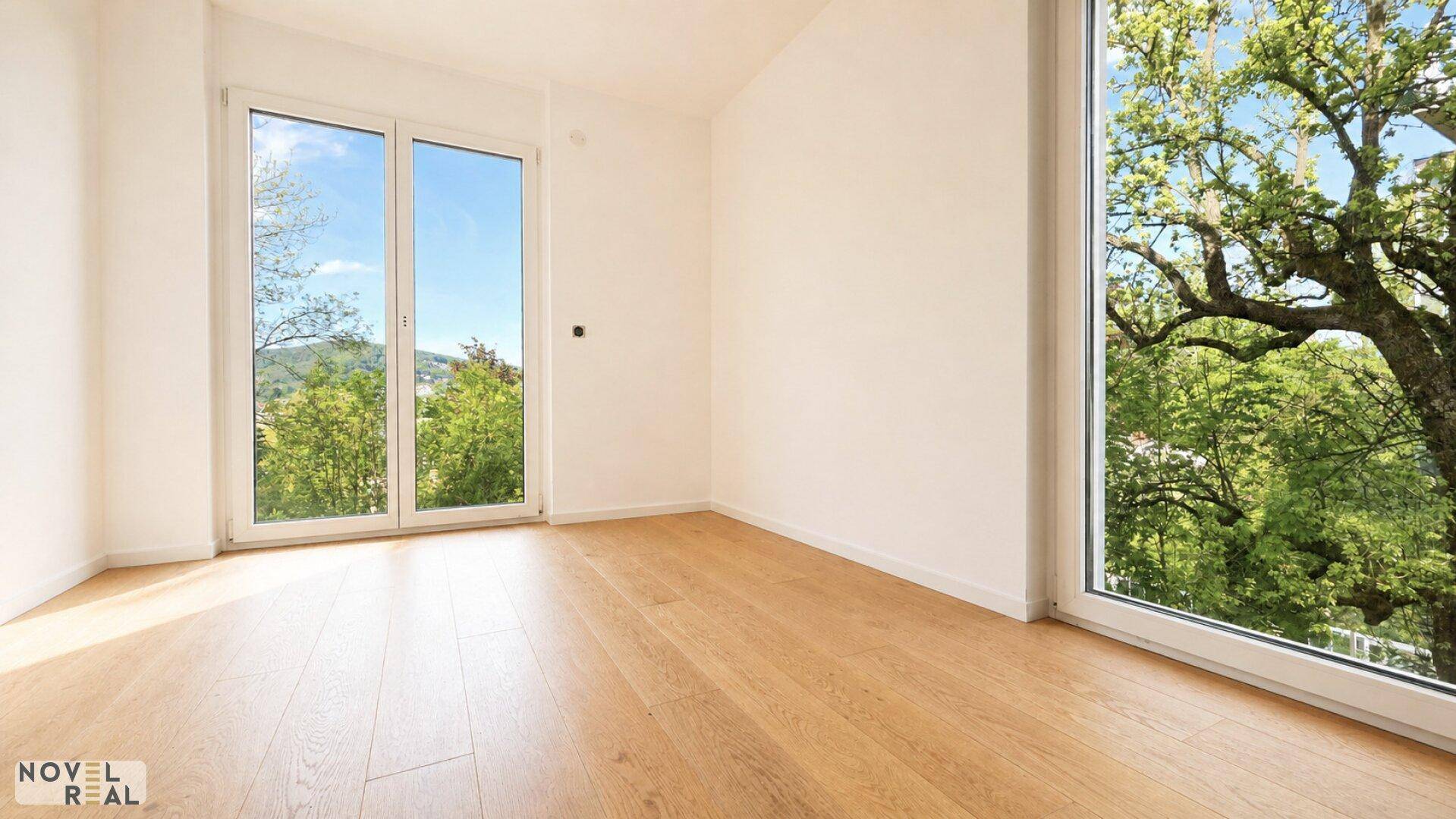 Lichtdurchflutetes Schlafzimmer mit Parkettboden und weitem Blick ins Grüne.