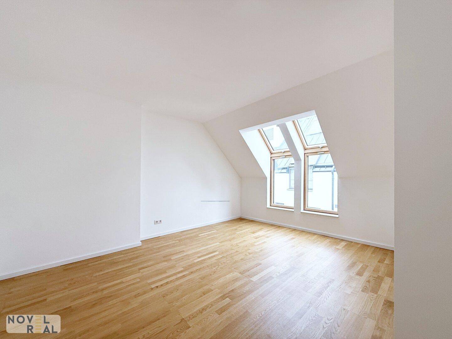 Helles Dachzimmer mit Parkettboden und weiß gestrichenen Wänden, ideal als Schlaf- oder Arbeitszimmer.