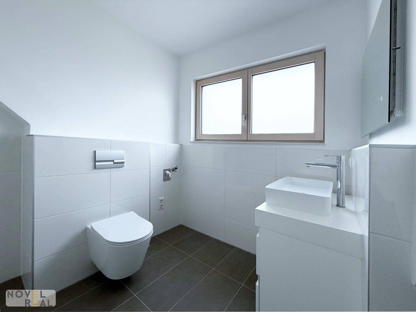 Separates Gäste-WC mit modernem Hänge-WC, Waschtisch und Fenster für Tageslicht.