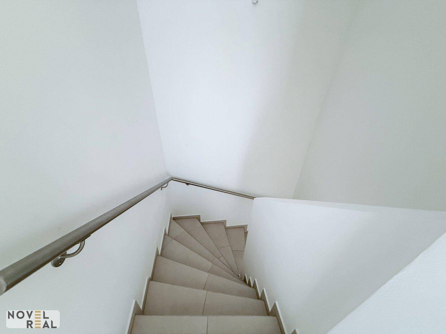 Wendeltreppe mit Fliesenstufen und schlichtem Geländer, die die verschiedenen Ebenen verbindet.