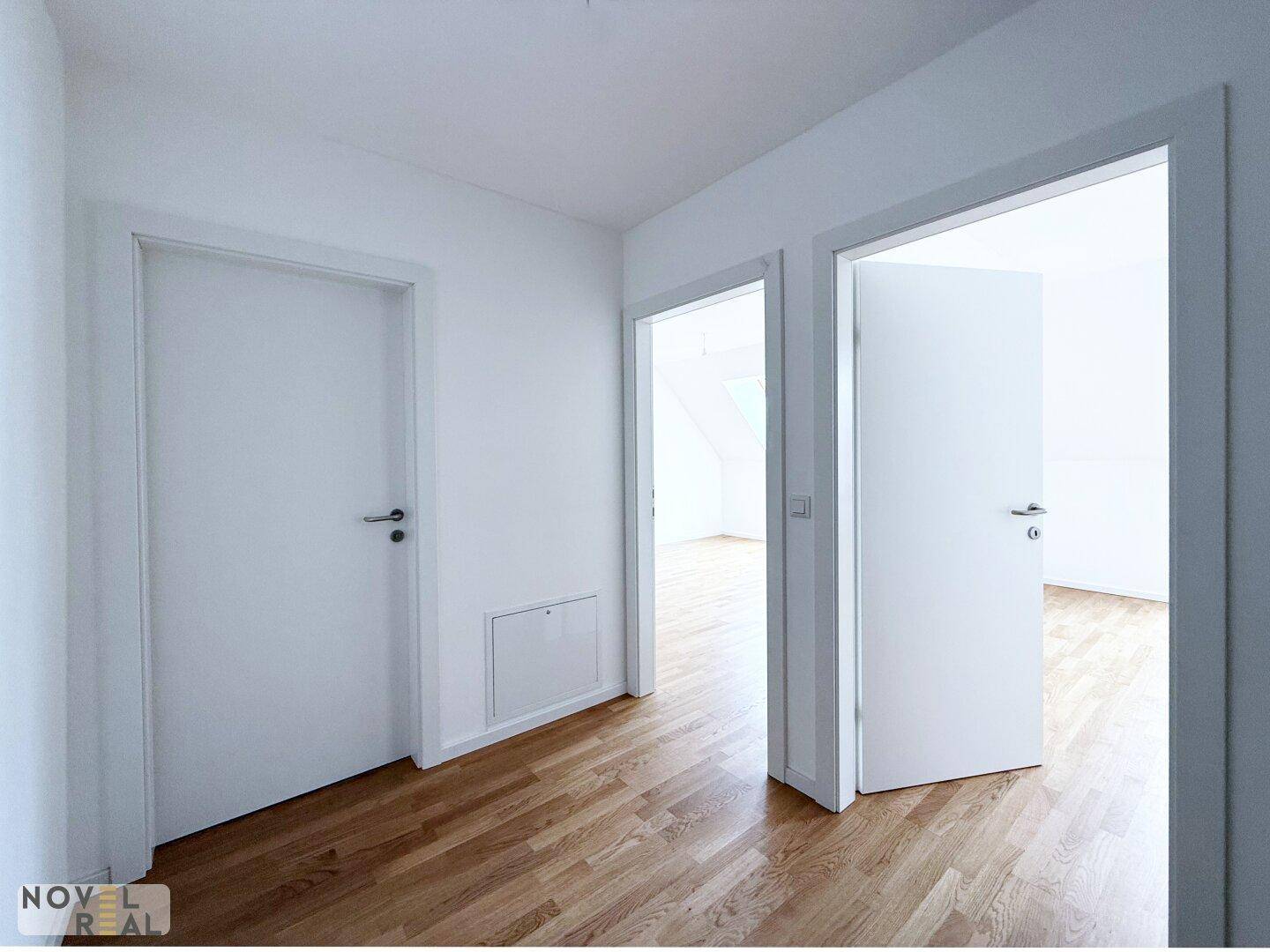 Heller Flur mit Holzboden und weißen Türen, der zu verschiedenen Räumen führt.
