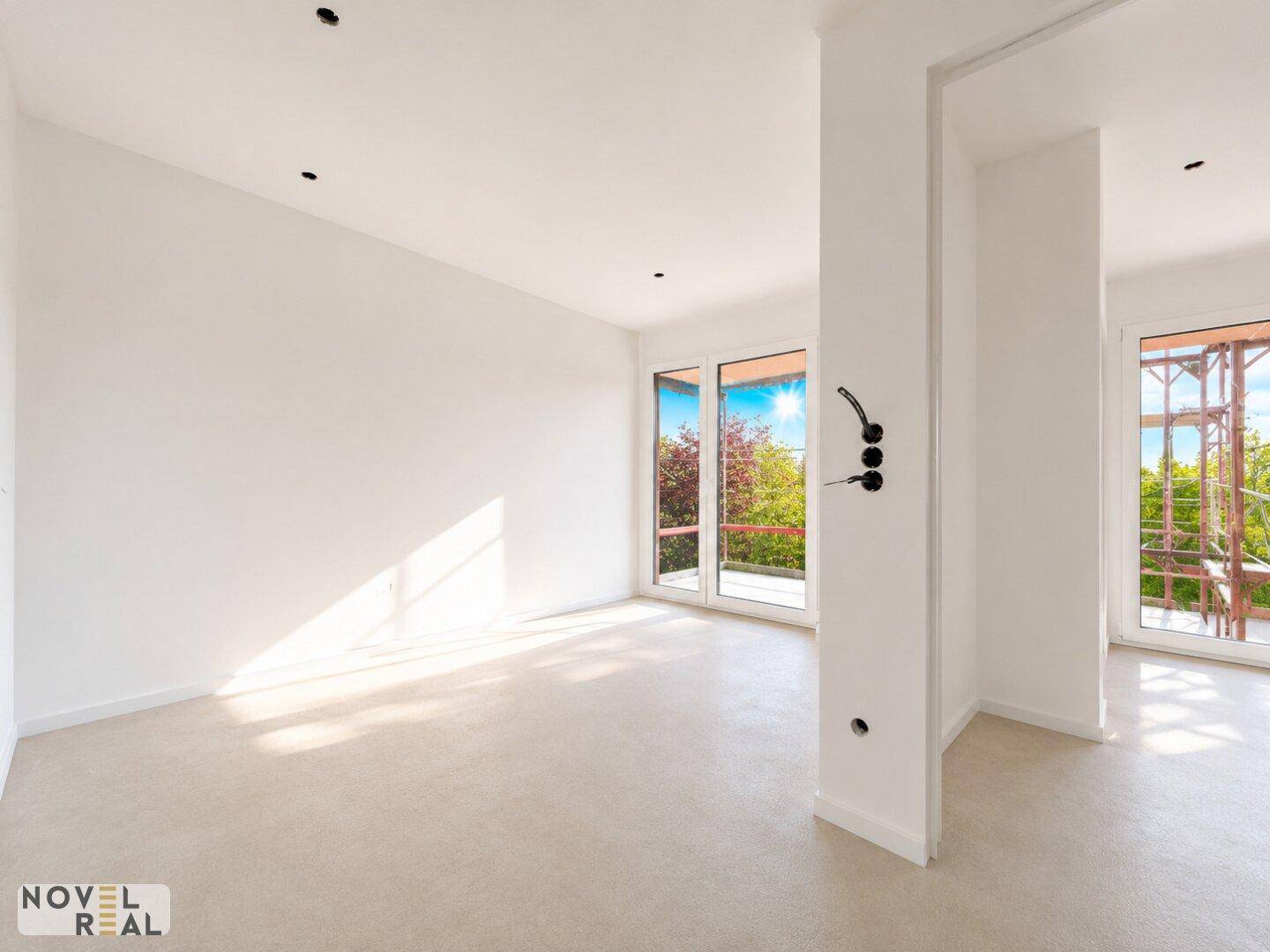 Lichtdurchfluteter Raum mit großen Fenstern und Blick ins Grüne, ideal für ein Wohnzimmer.