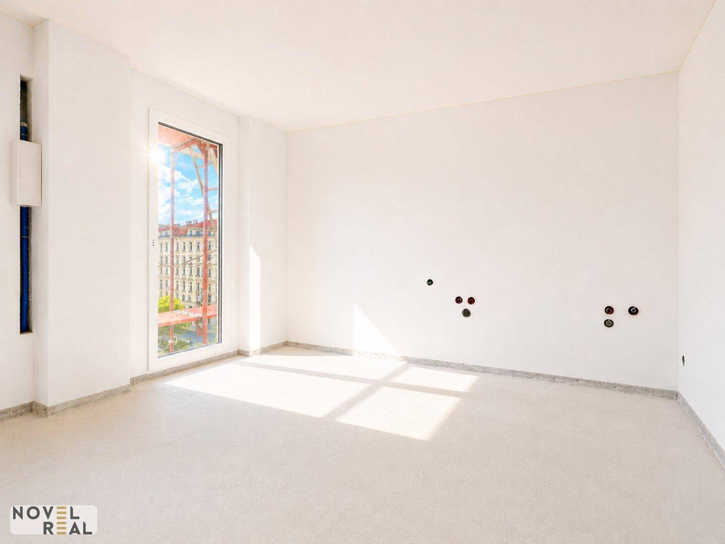 Heller, leerer Raum mit einem Fenster und vorbereiteten Anschlüssen an der Wand.