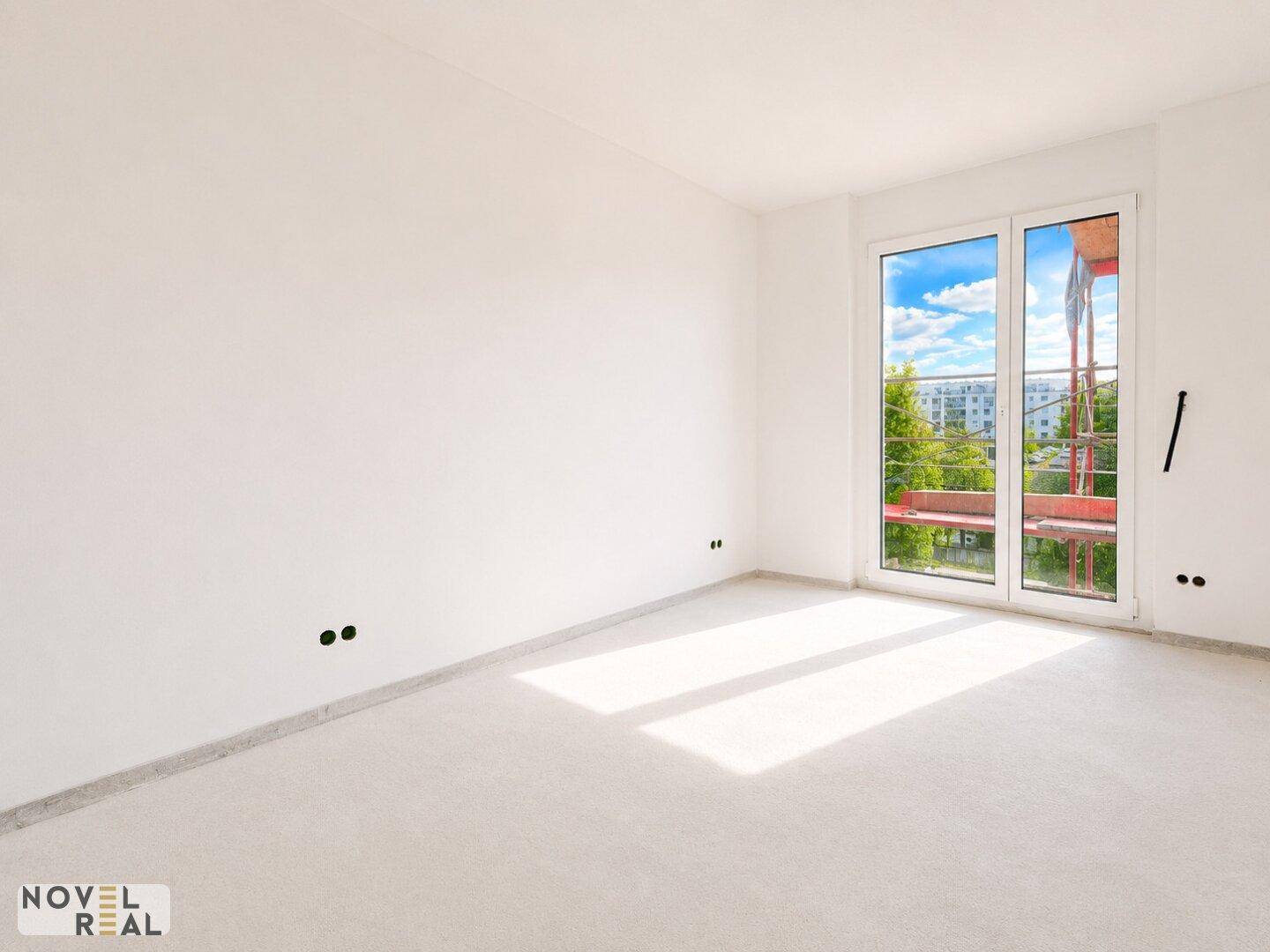 Leerer, heller Raum mit einem großen Fenster, das viel Tageslicht hereinlässt.