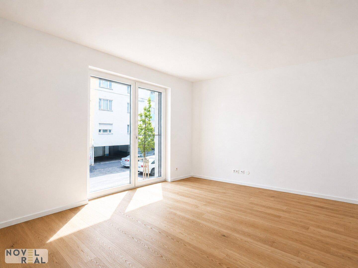 Lichtdurchfluteter Raum mit Holzboden und Blick ins Grüne, bereit für die Einrichtung.