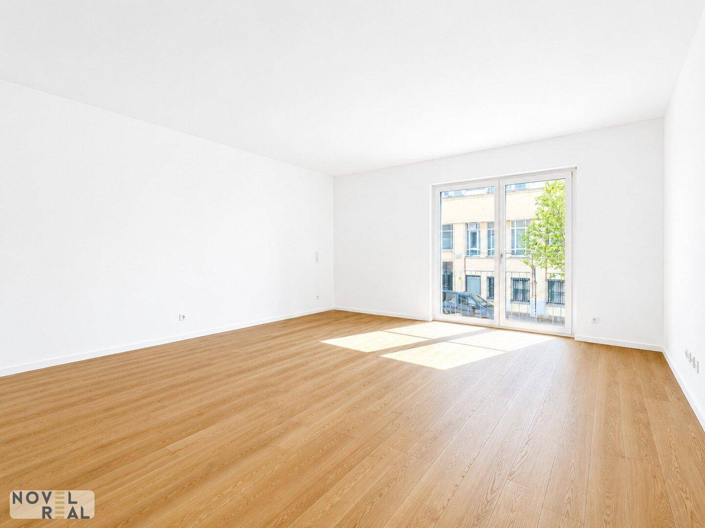 Helles, leeres Zimmer mit großen Fenstern und hellem Holzparkettboden, ideal für individuelle Gestaltung.