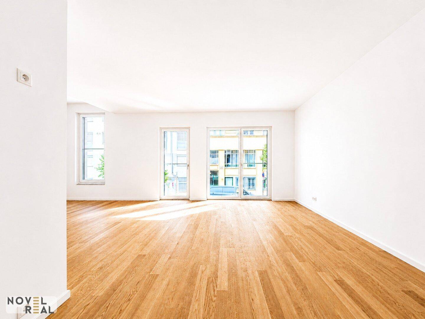 Geräumiges, helles Zimmer mit Parkettboden und großen Fenstern, die einen Blick auf die Umgebung bieten.