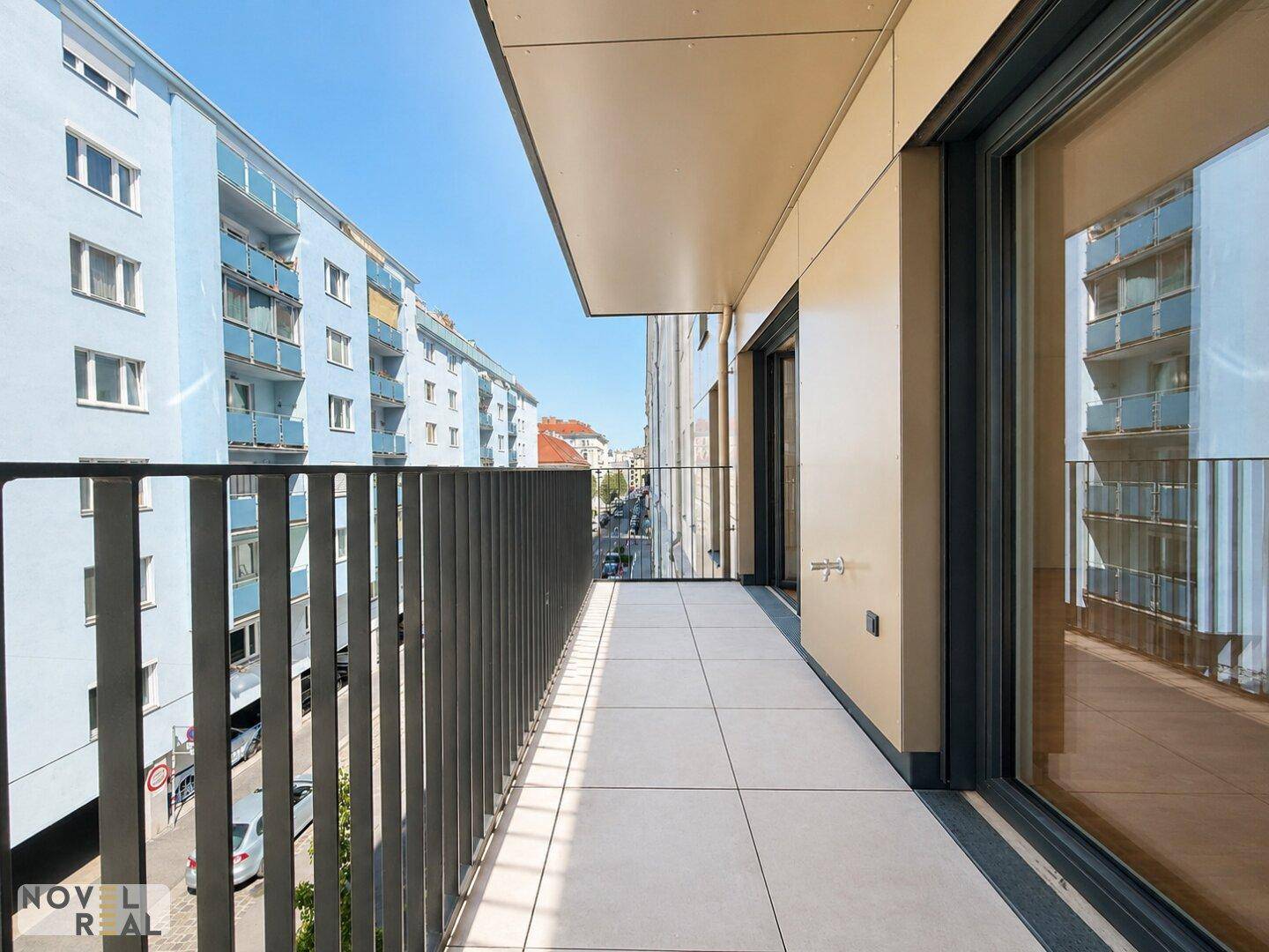 Geräumiger Balkon mit Fliesenboden und weitem Blick über die städtische Umgebung und angrenzende Gebäude.