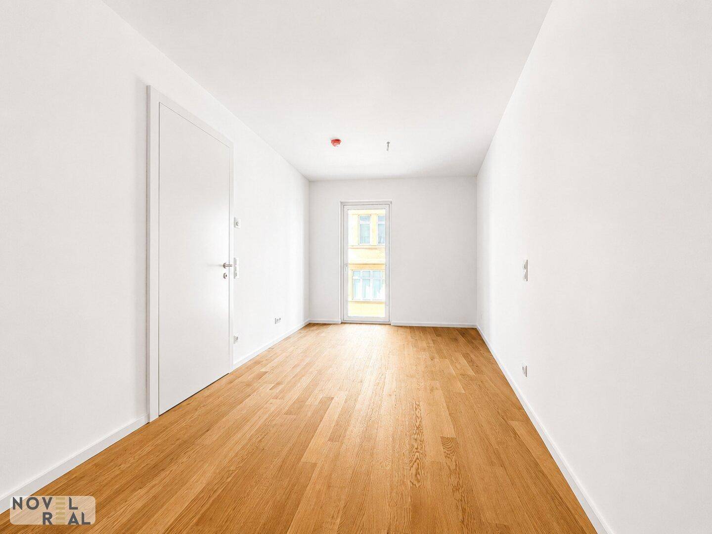 Unmöbliertes Zimmer mit Eichenparkett und Balkonzugang, bietet viel Potenzial für individuelle Gestaltung.