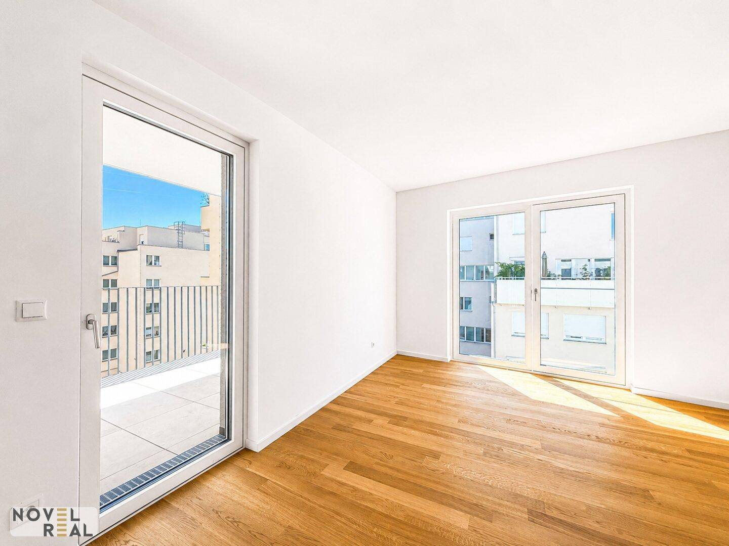 Helles Schlafzimmer mit Parkettboden und direktem Zugang zu einem sonnigen Balkon.