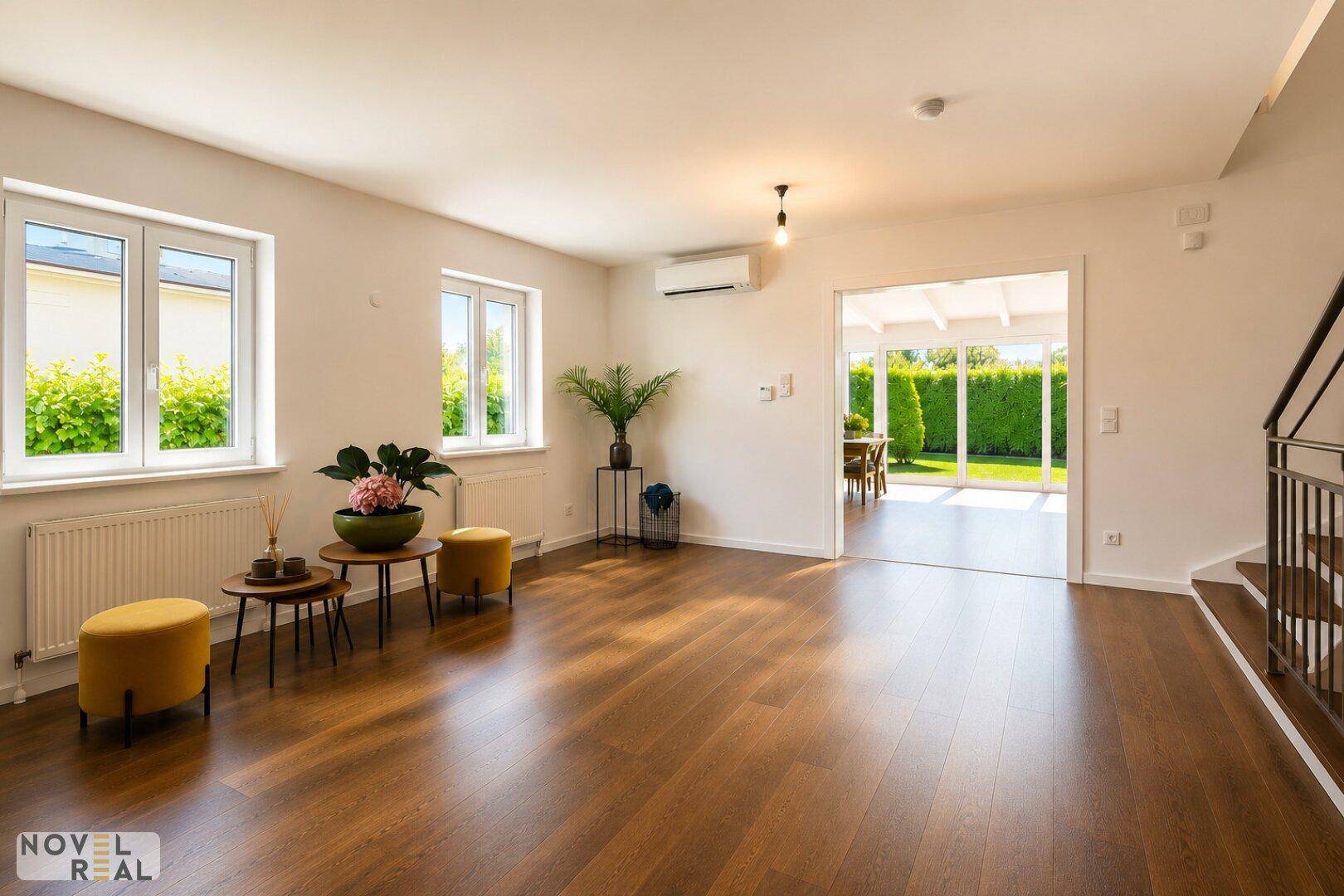 Geräumiger Wohnbereich mit Holzboden, Klimaanlage und offenem Zugang zum Wintergarten.