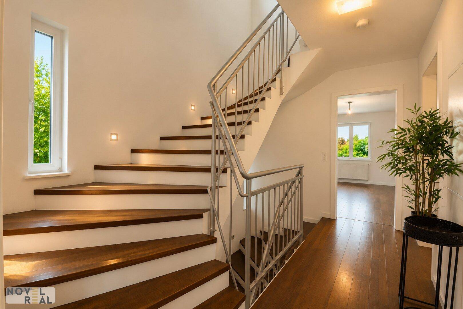 Elegante Holztreppe mit Metallgeländer und integrierter Beleuchtung im Flurbereich.