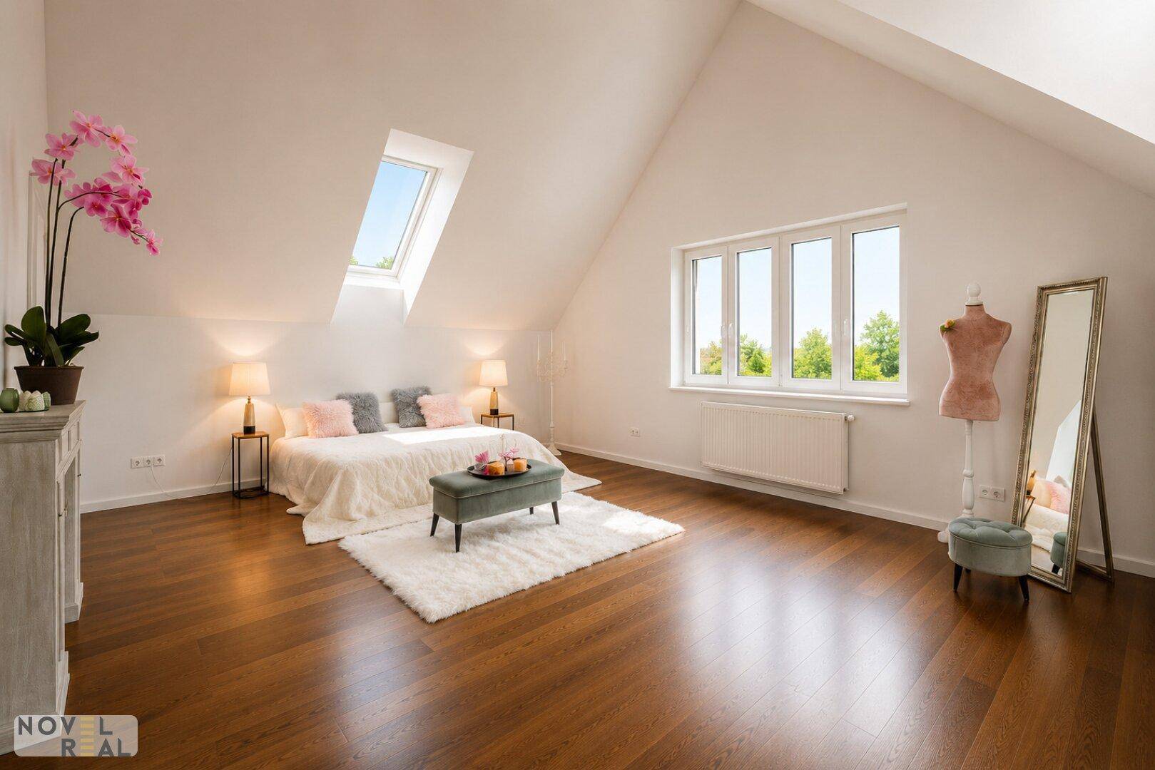 Helles Schlafzimmer im Dachgeschoss mit Holzboden, Dachfenster und Blick ins Grüne.