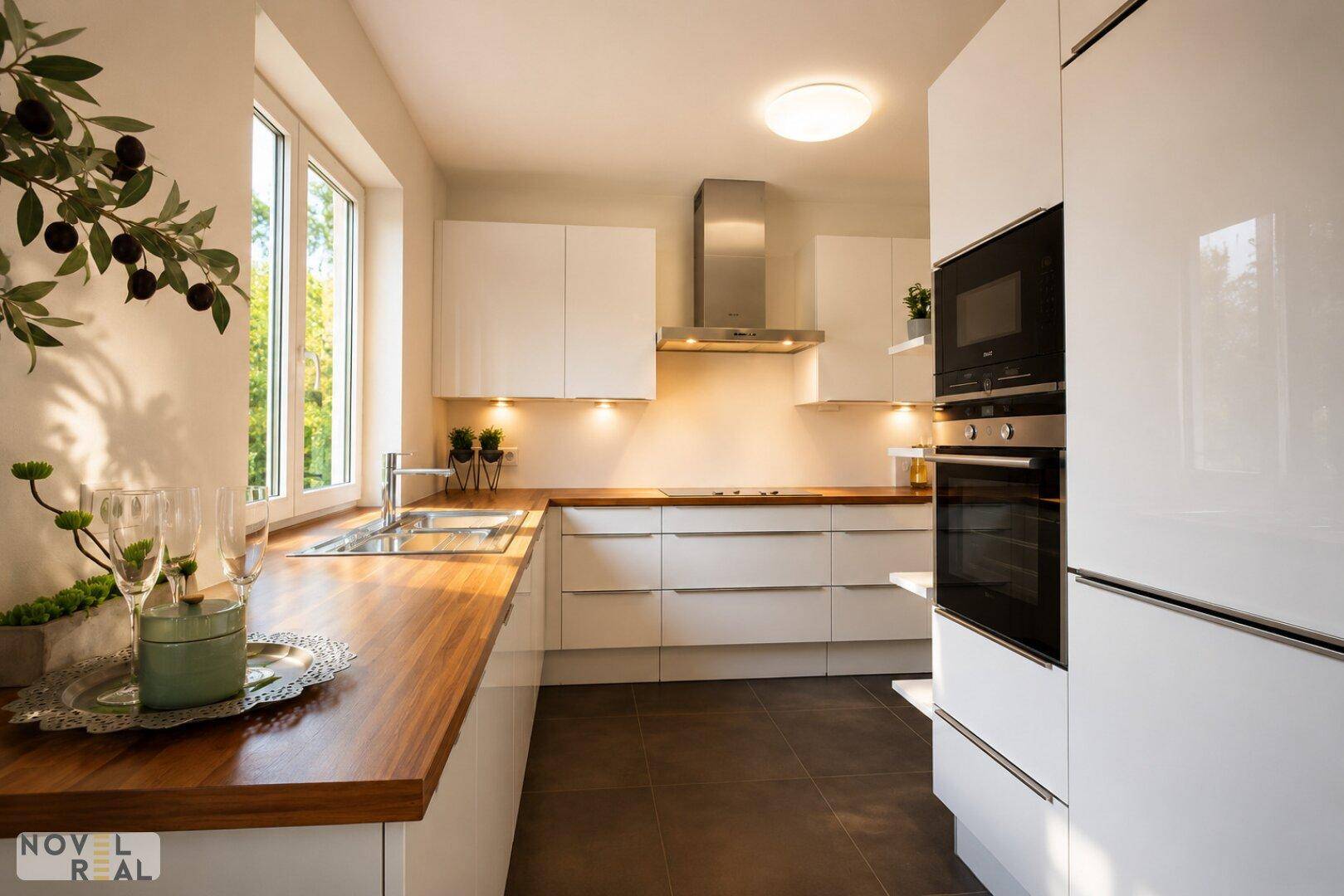 Moderne Einbauküche mit weißen Hochglanzfronten, Holzarbeitsplatte und Fenster.
