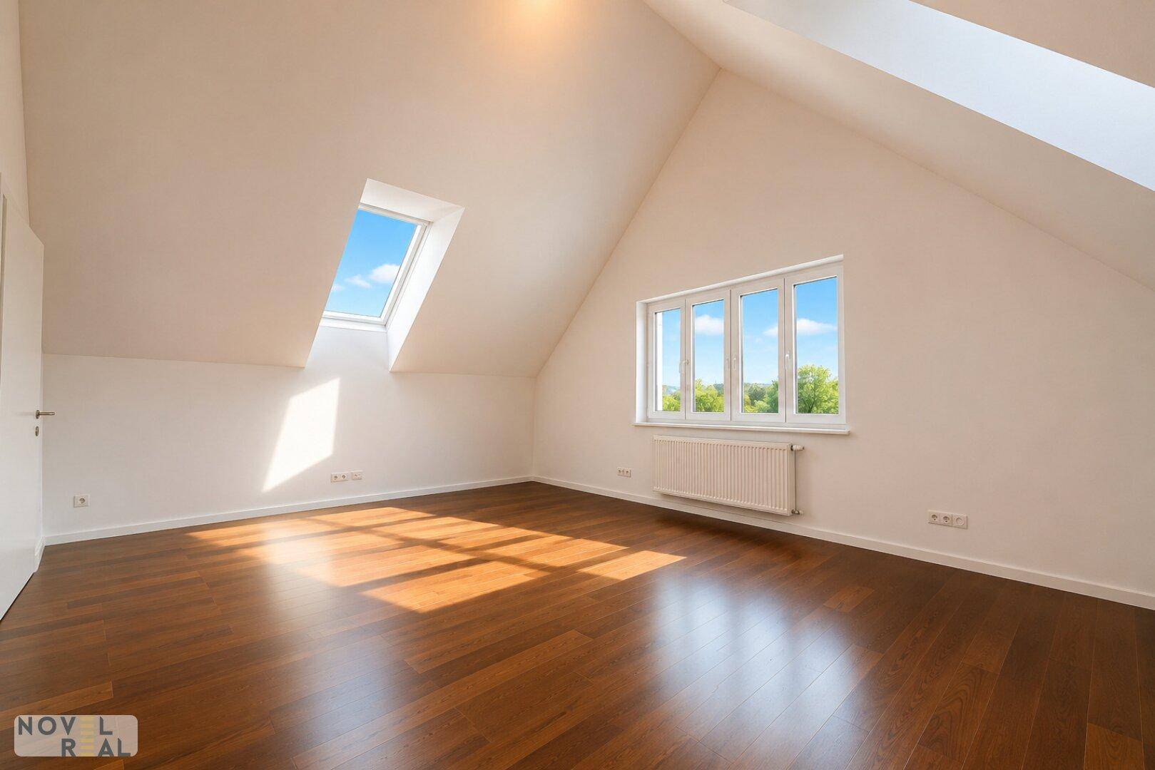Heller Raum im Dachgeschoss mit Holzboden, Dachfenstern und viel Tageslicht.