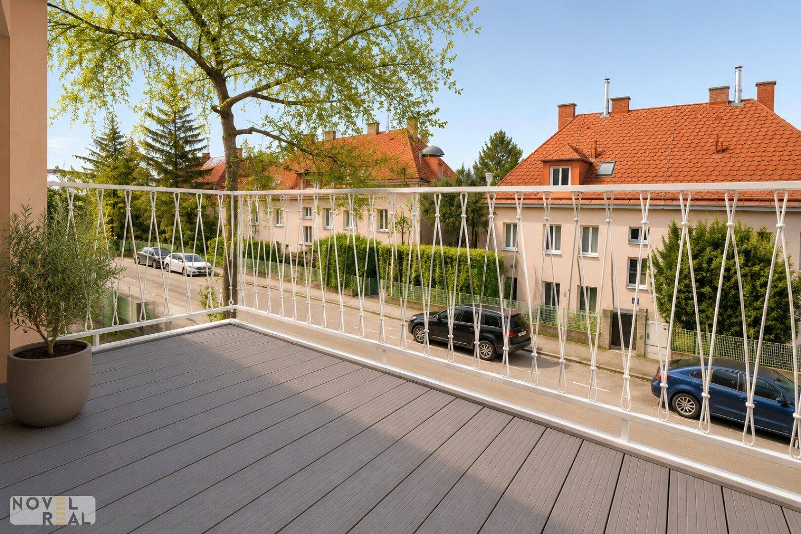 Heller Balkon mit modernem Bodenbelag und Blick auf die Straße und Bäume.