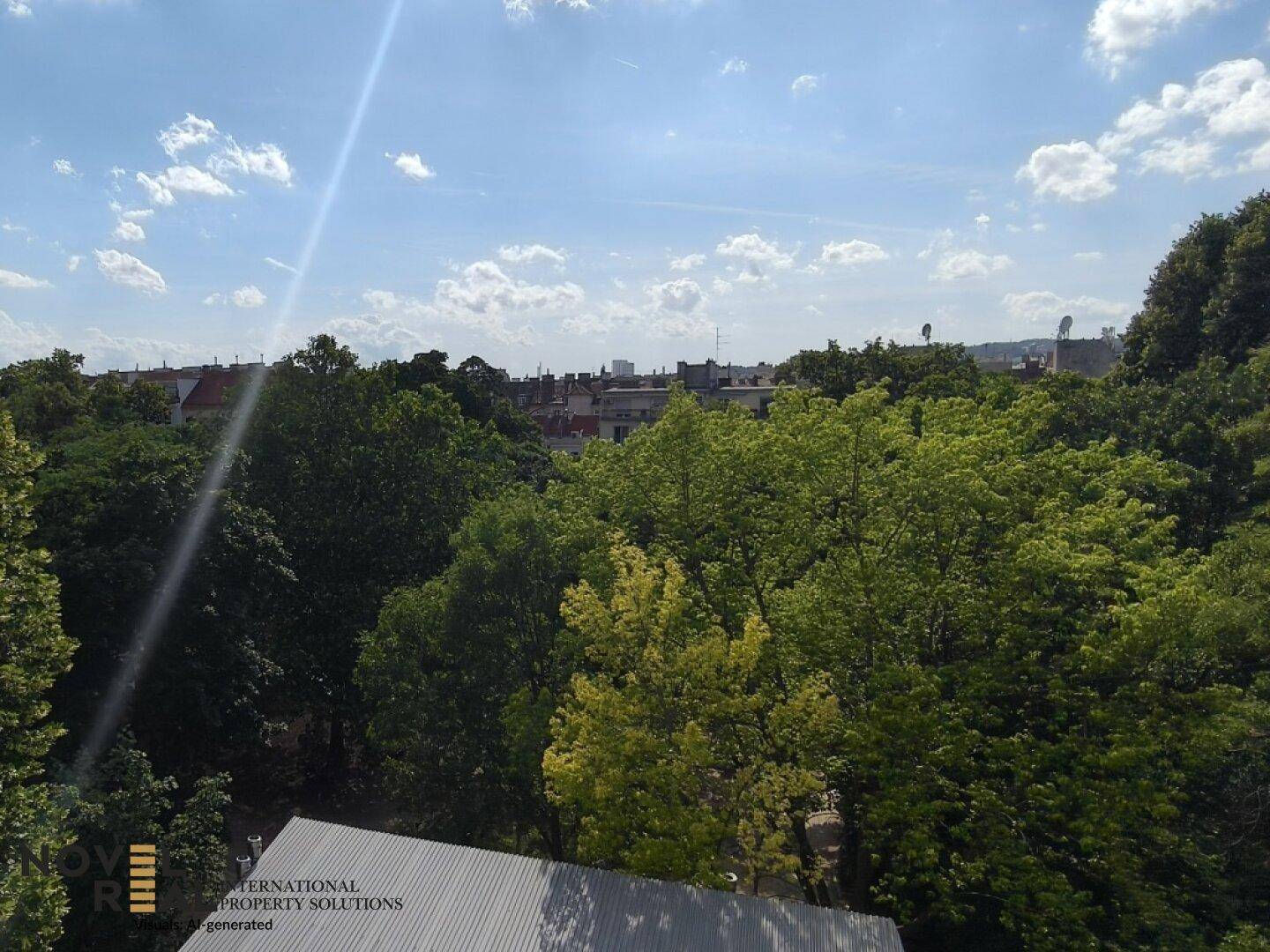 Weitläufiger Blick über grüne Baumwipfel und die Dächer der Stadt unter blauem Himmel.