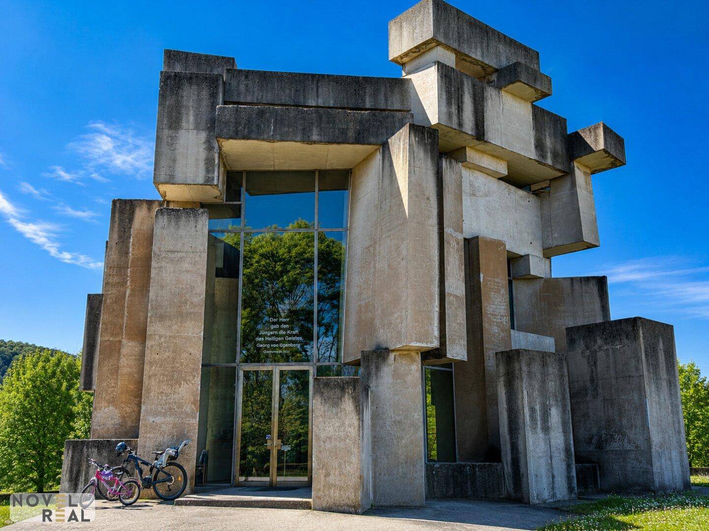 Frontansicht des brutalistischen Gebäudes mit großer Glasfassade und Eingangsbereich.