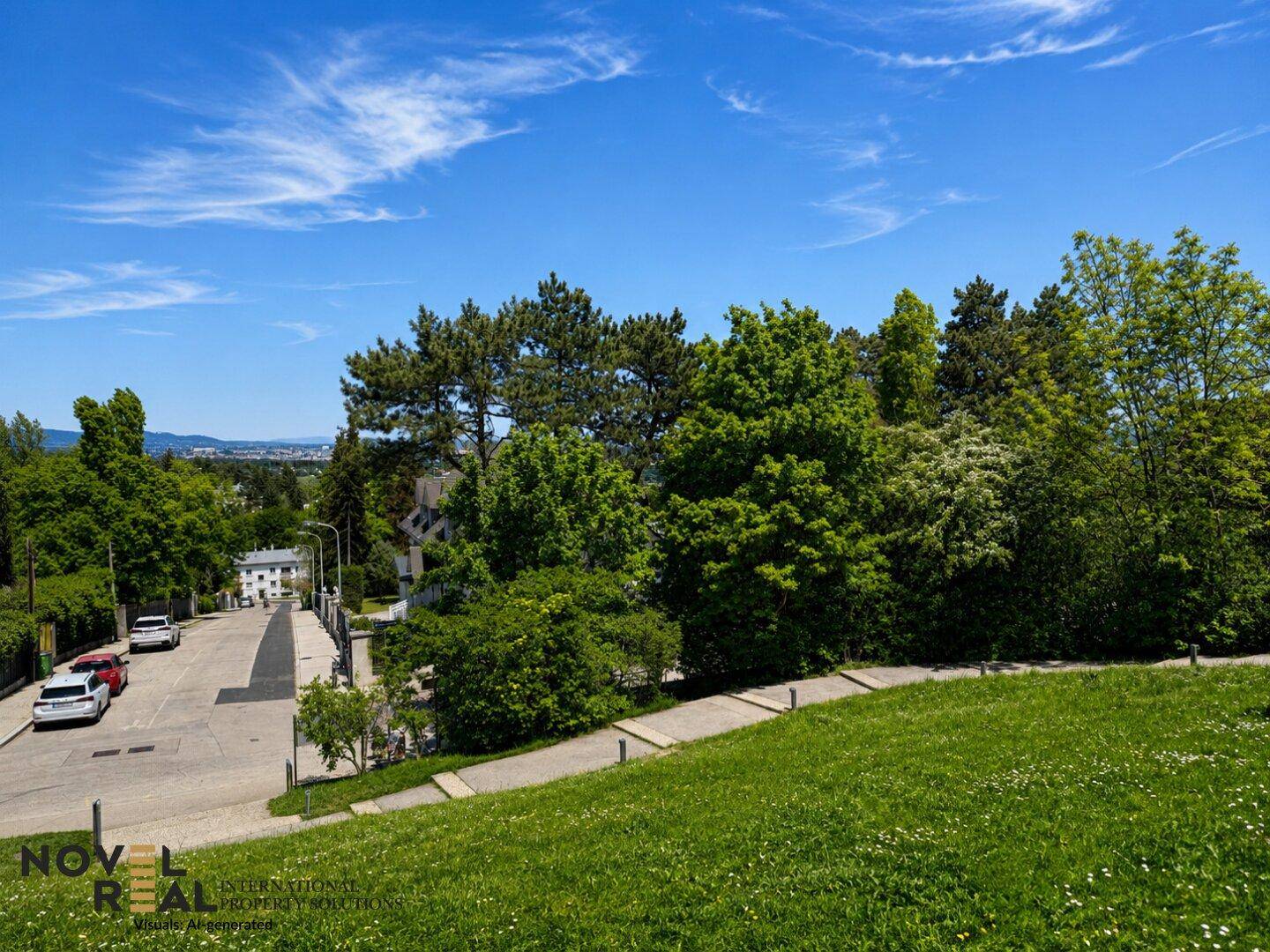 Grüne Hanglage neben einer Wohnstraße mit Bäumen und einem weiten Blick auf die Stadt in der Ferne.