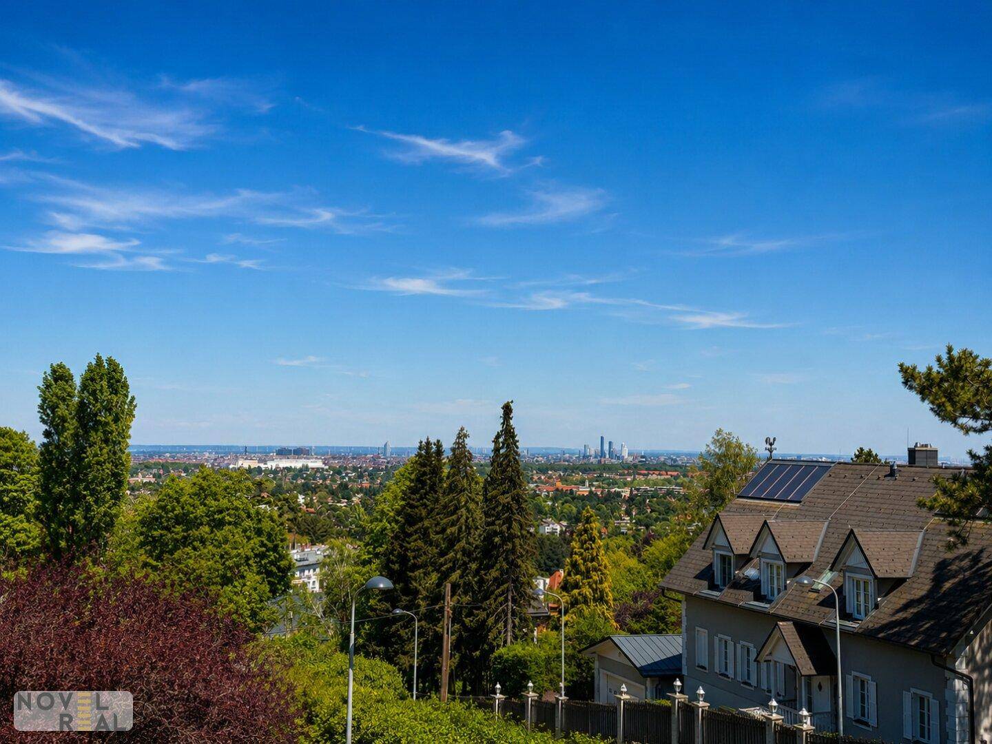Weitläufige Aussicht auf die Stadt und die umliegende grüne Natur unter blauem Himmel.