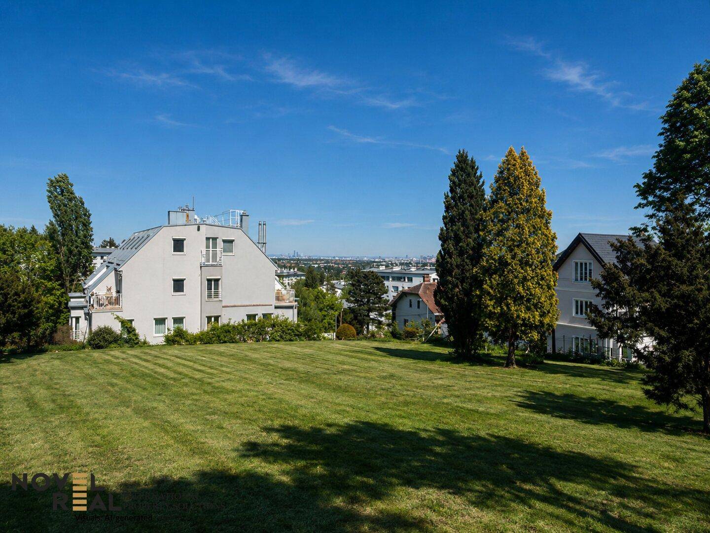 Große, gepflegte Rasenfläche mit Wohnhäusern und einem weiten Blick auf die Stadt in der Ferne.