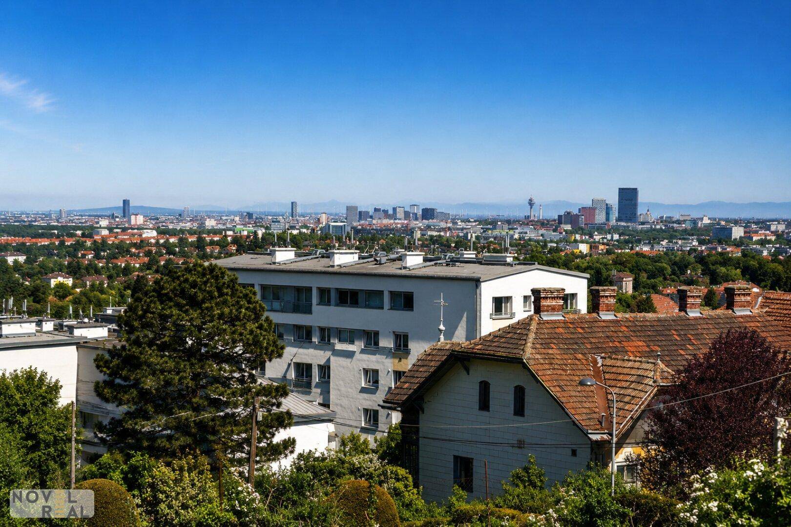 Fernblick über die Stadt mit Wohngebäuden im Vordergrund unter blauem Himmel.