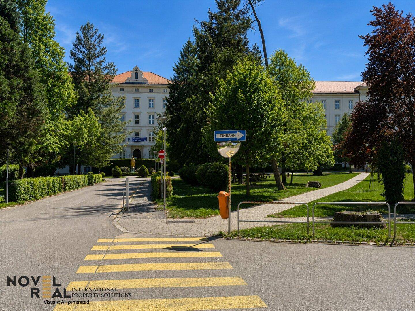 Straßenkreuzung mit Zebrastreifen und einem großen, klassischen Gebäude im Hintergrund, umgeben von Grün.