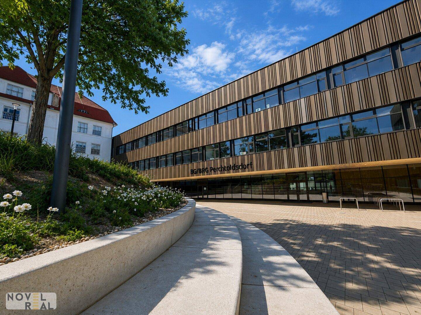 Modernes Gebäude mit Holzfassade und großzügigem Eingangsbereich unter blauem Himmel.