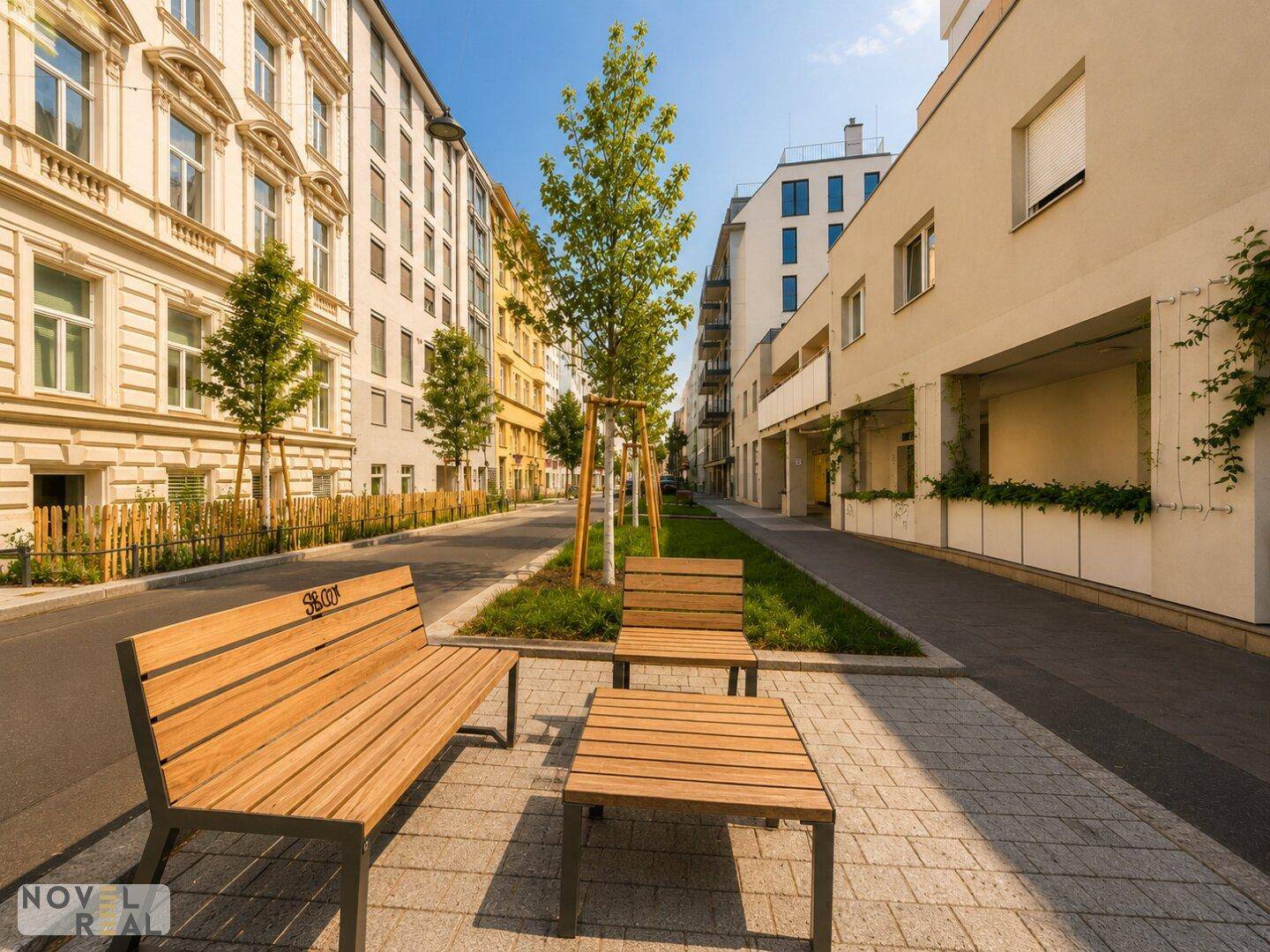 Öffentlicher Außenbereich mit Holzbänken und Tischen, umgeben von Grünflächen und städtischer Architektur.