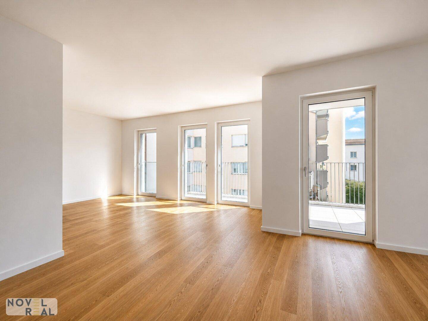 Lichtdurchfluteter Raum mit hellem Parkettboden und Zugang zu einem großzügigen Balkon.